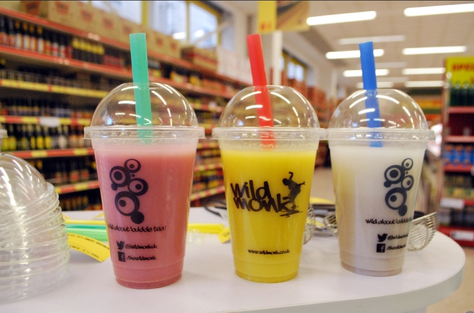 Three bubble tea drinks on display during an in-store sampling event, each with colorful straws and branded cups.