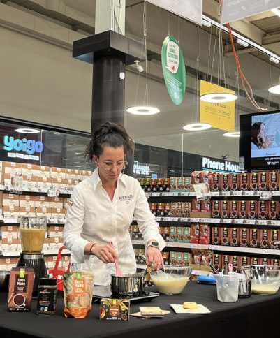 Chef Carito Lourenço conducting a live cooking demonstration at Alcampo, preparing a dessert with fair trade Tierra Madre Oxfam Intermón products.